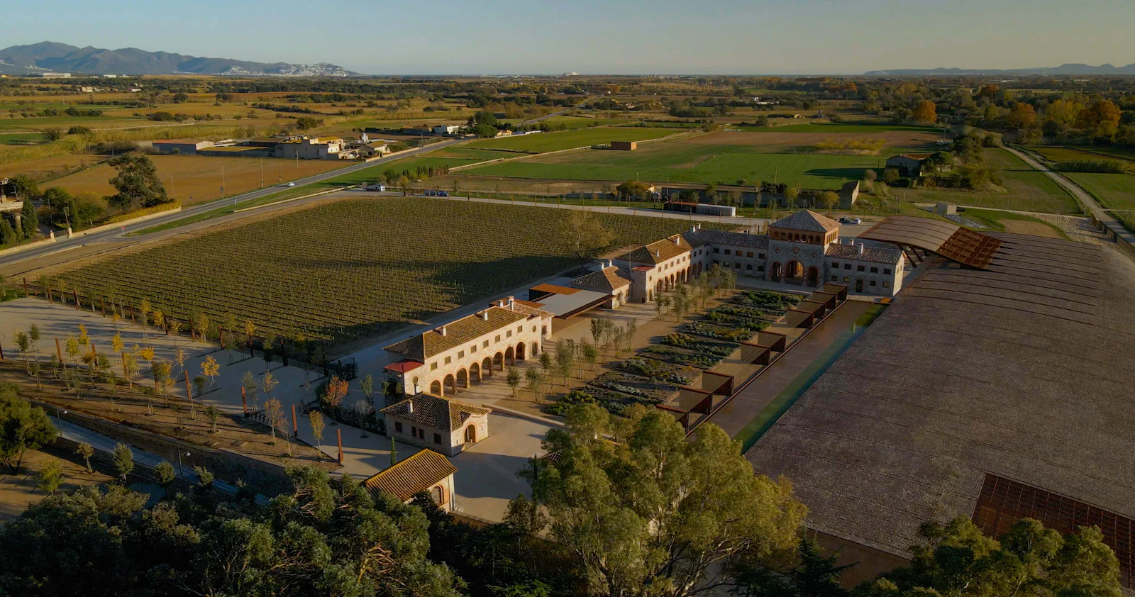 Aerial view of a winery estate with vineyards, courtyards and distant mountains.