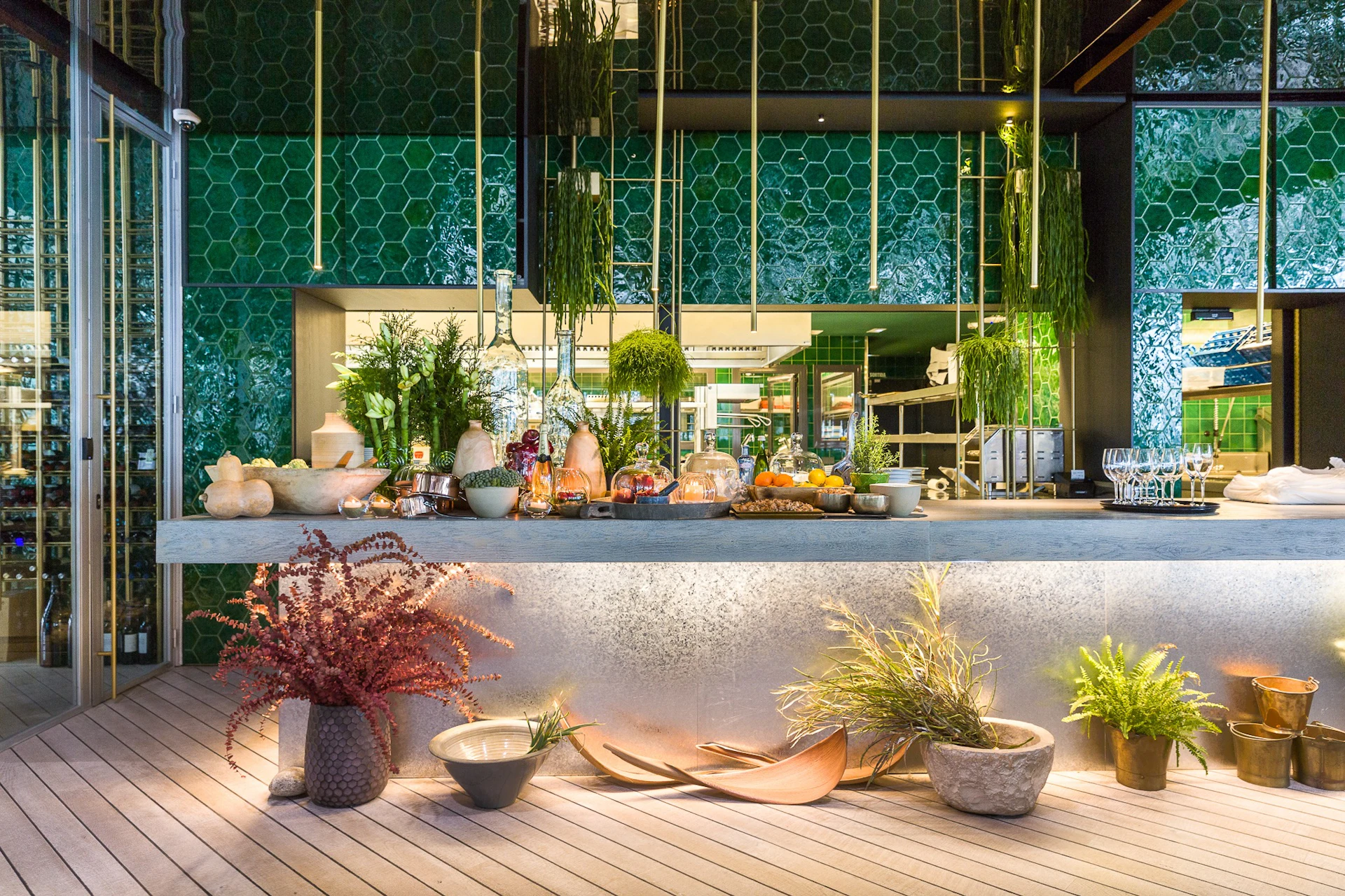 Terraza de restaurante moderno en la marina con plantas en macetas, suelo de madera y elegante barra con vistas al agua.