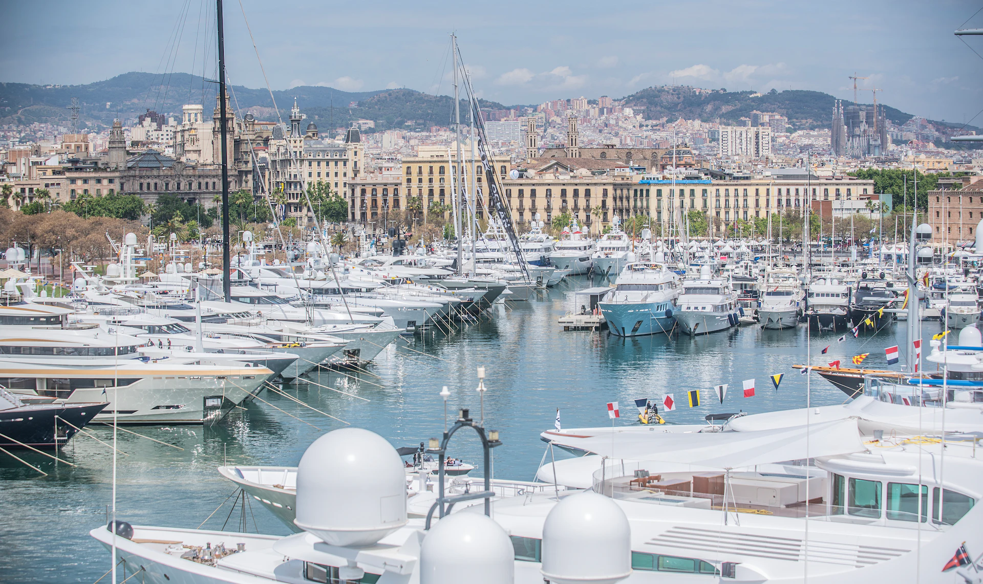 Horizonte de Barcelona y puerto lleno de superyates blancos y veleros amarrados.