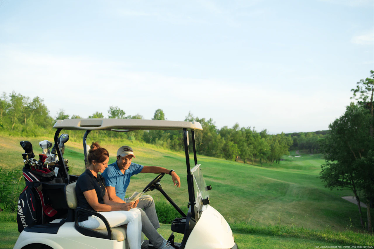 Imagen de dos golfistas en un buggy o carro de golf transportando sus palos de golf de camino al siguiente hoyo.