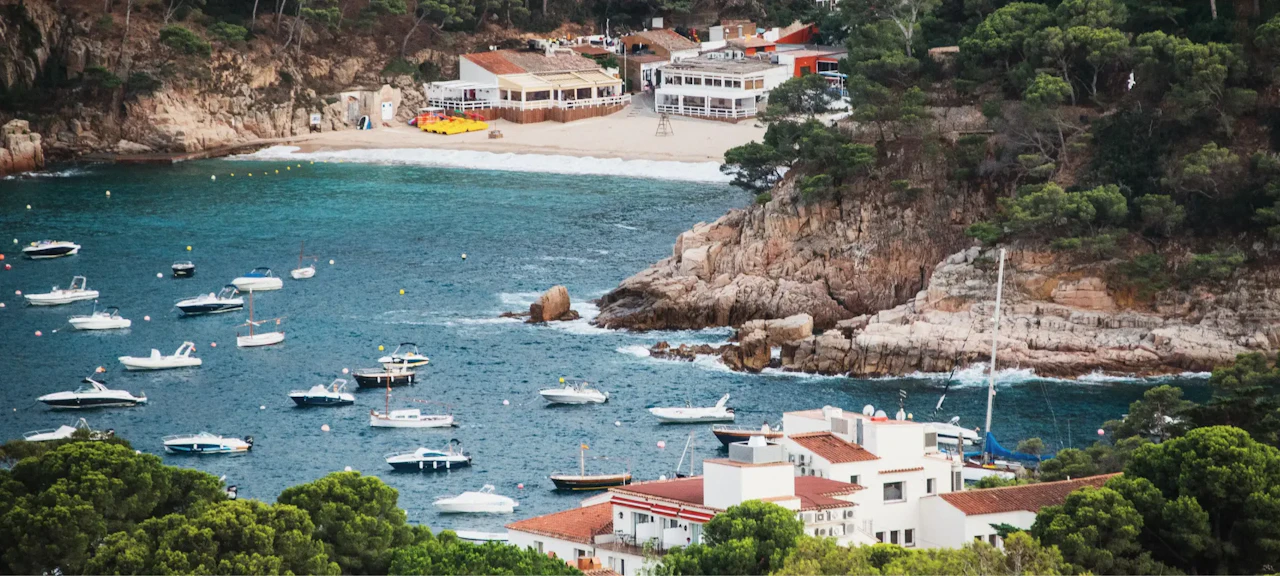 Vista aérea de Cala Aiguablava con aguas cristalinas, barcos en reposo y un entorno natural que refleja la esencia de la Costa Brava.