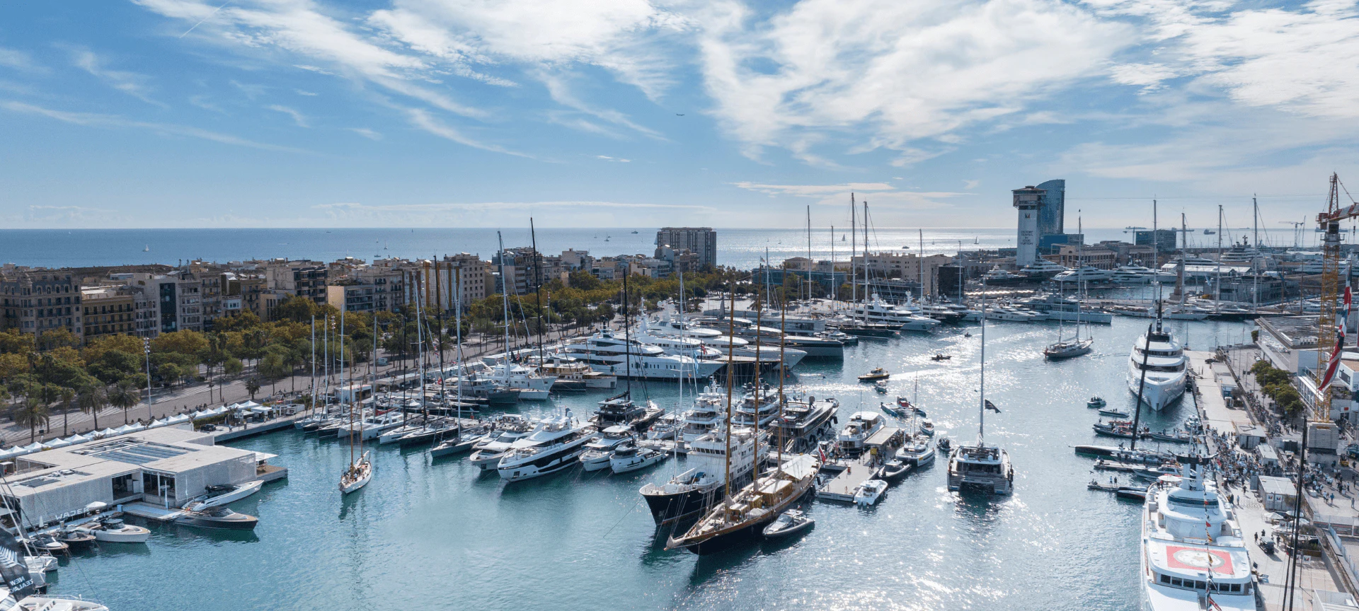 Vista aérea de Marina Port Vell con numerosos veleros y yates amarrados en el frente marítimo de Barcelona.
