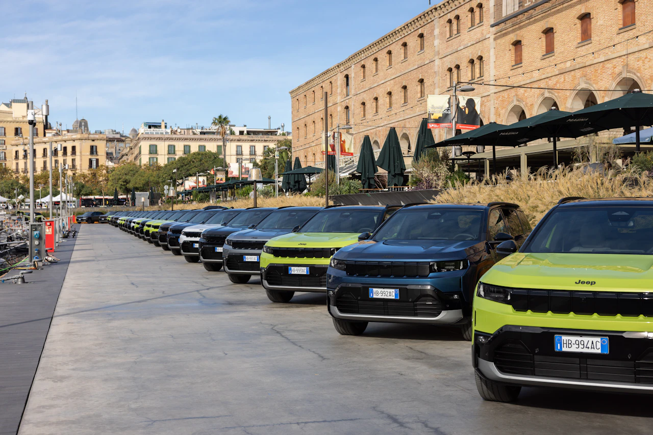 Row of Jeep SUVs parked along a marina promenade with buildings behind.