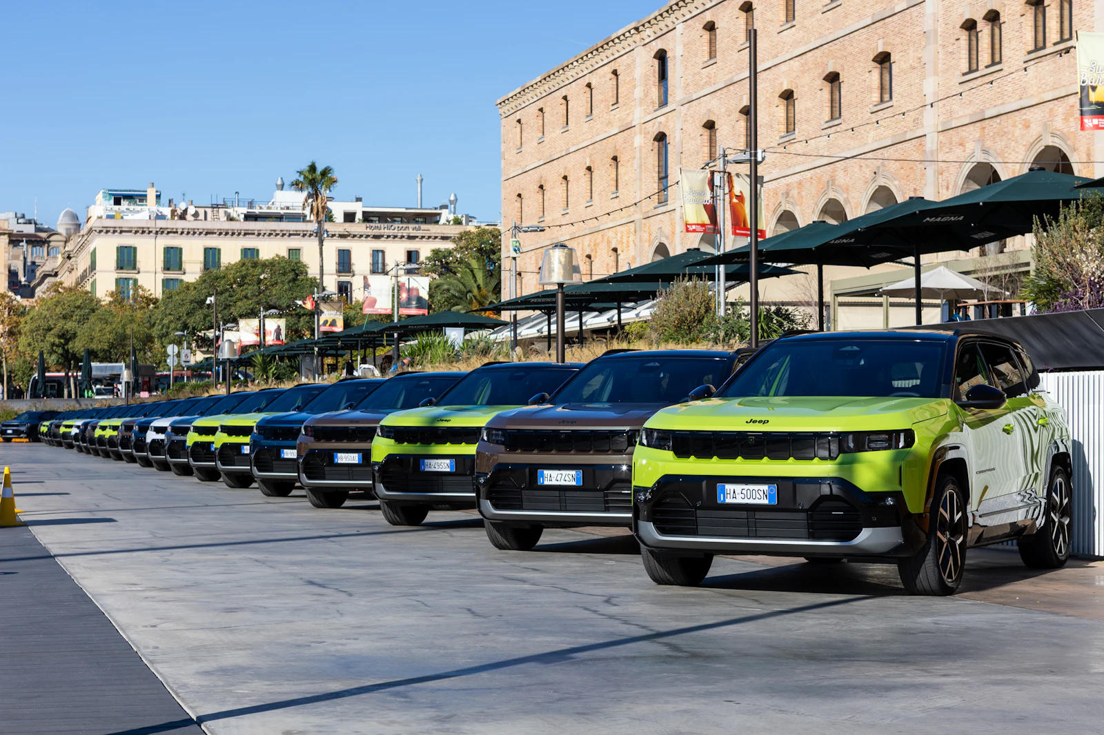 Row of green Jeep SUVs parked in front of a stone building.