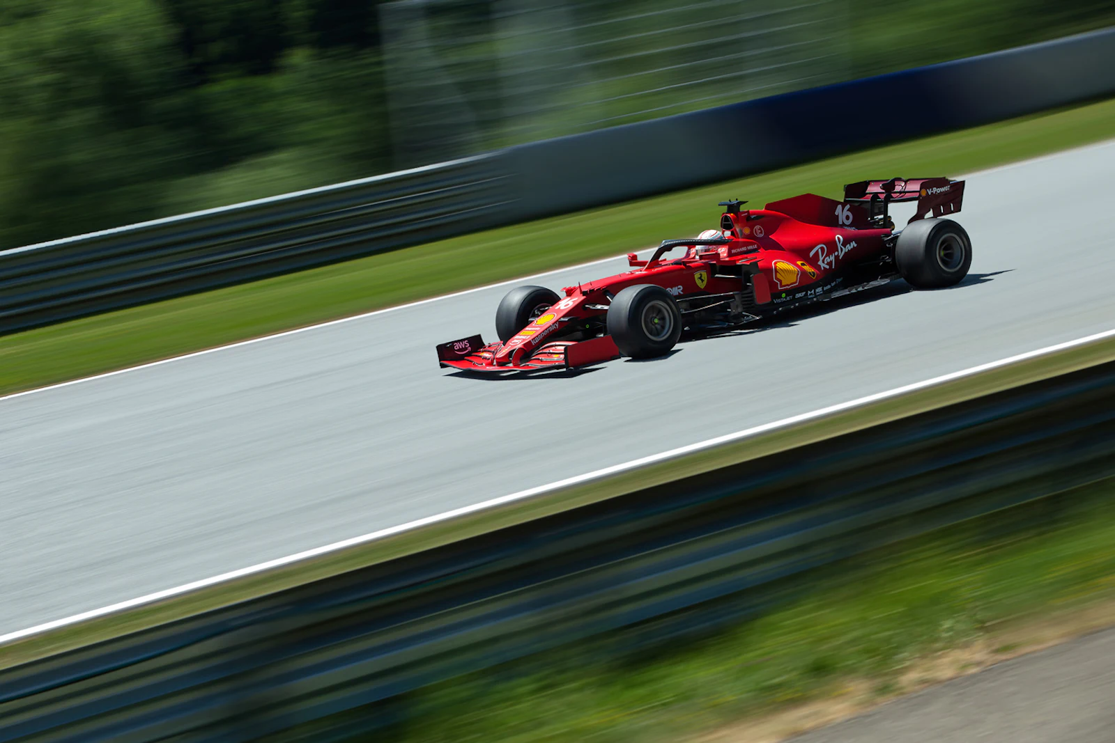 Red Ferrari Formula One car racing on a track with green surroundings.