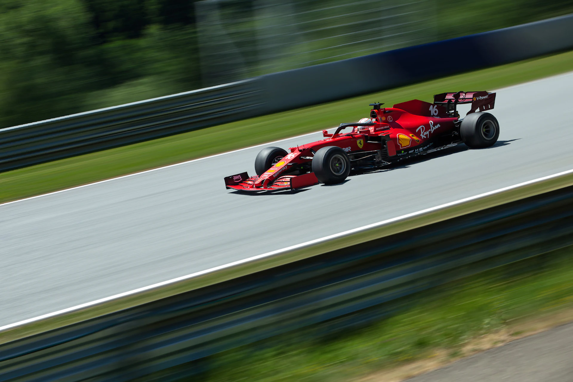 Coche de Fórmula 1 Ferrari rojo compitiendo en un circuito con entorno verde.