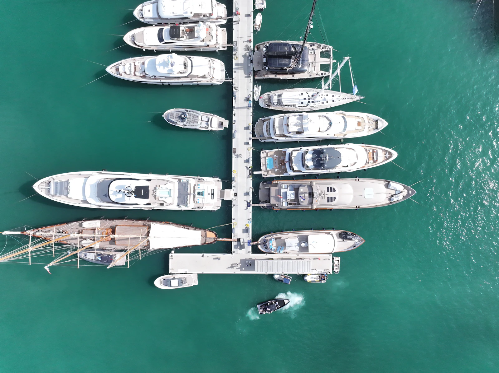 Aerial view of multiple superyachts moored at a marina dock in turquoise water.