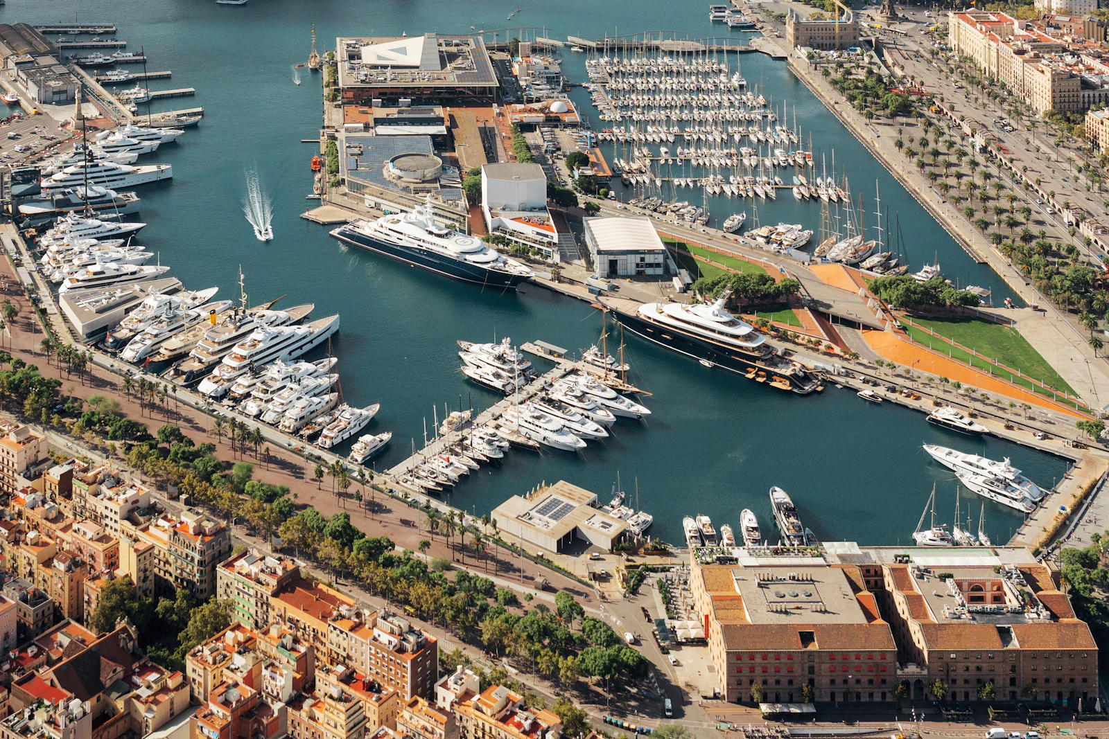 Aerial view of a marina full of yachts beside Barcelona's waterfront buildings.
