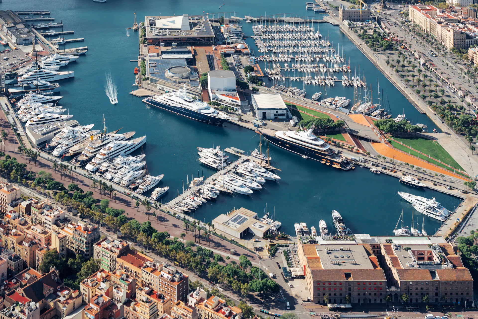 Aerial view of Marina Port Vell showing numerous moored superyachts and sailboats in Barcelona's harbor.