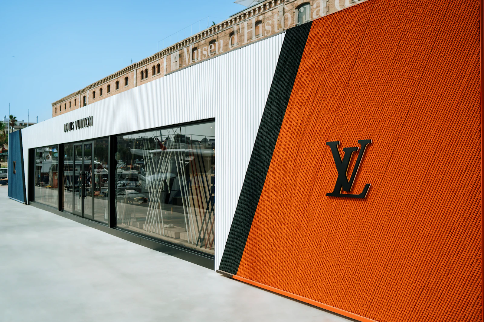 Louis Vuitton boutique storefront with orange ribbed facade and glass windows at a marina.