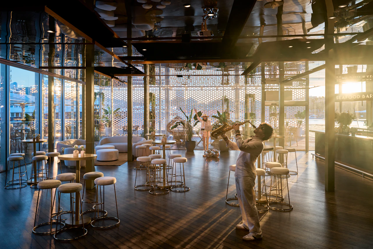 Modern lounge bar with floor-to-ceiling windows overlooking Barcelona cityscape and marina.