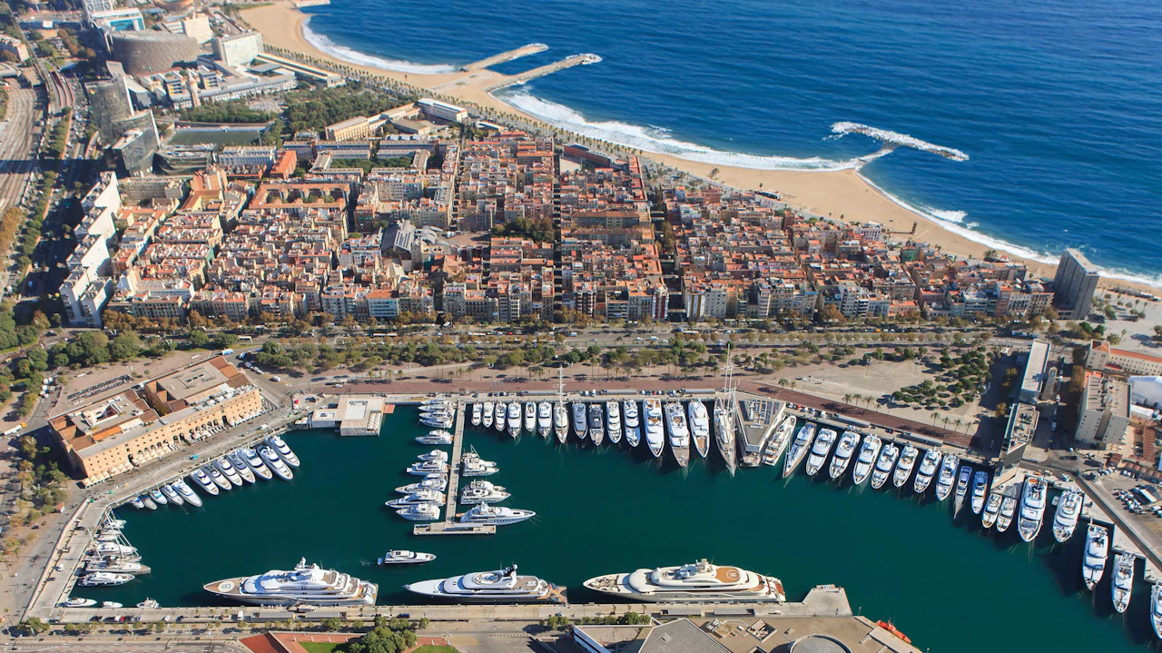 Aerial view of Marina Port Vell showing multiple superyachts moored in Barcelona's waterfront basin.