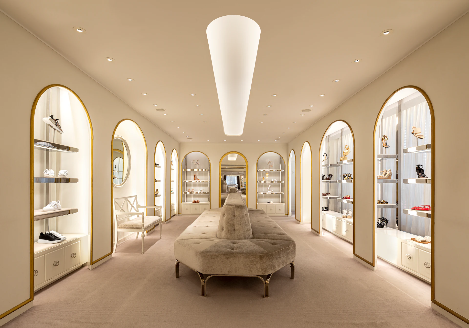 Luxury boutique interior with arched gold-framed display cases and central seating.