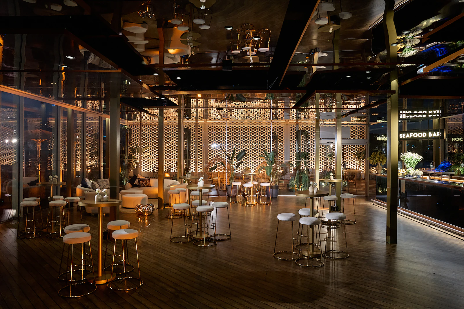 Dimly lit lounge with high stools, cocktail tables and a seafood bar.