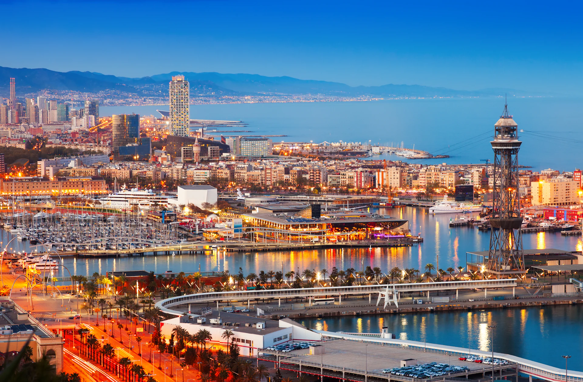 Vista aérea del puerto y la marina de Barcelona con la torre del teleférico al atardecer.