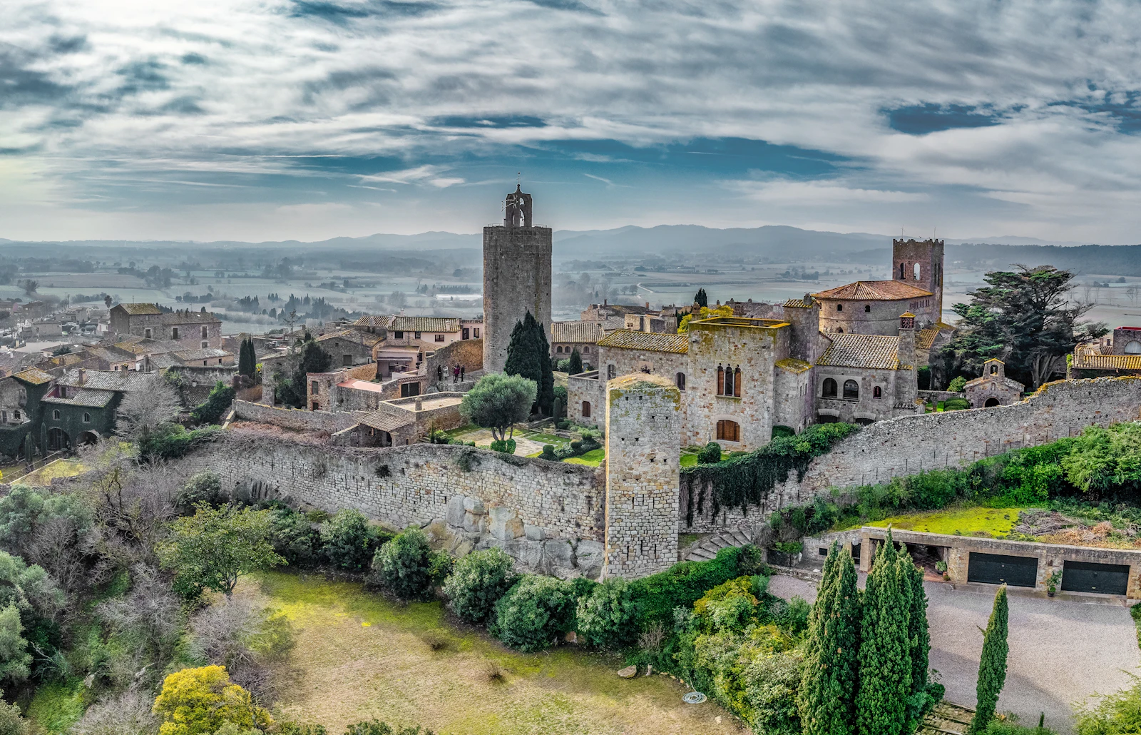 Medieval walled town with stone towers overlooking a misty countryside landscape.