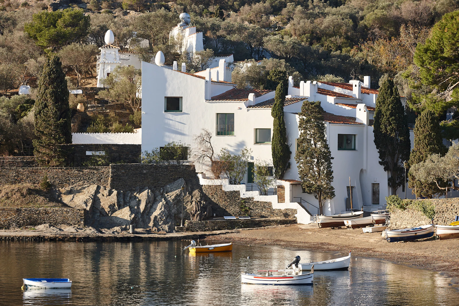 Whitewashed hillside houses overlooking a calm bay with small fishing boats.