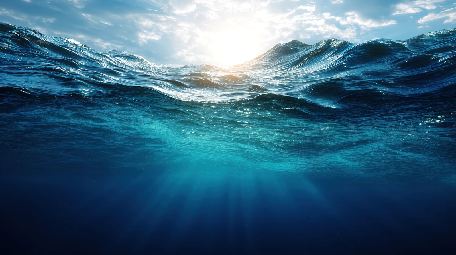 Vista submarina de la superficie del océano con luz solar filtrándose a través de las olas ondulantes.
