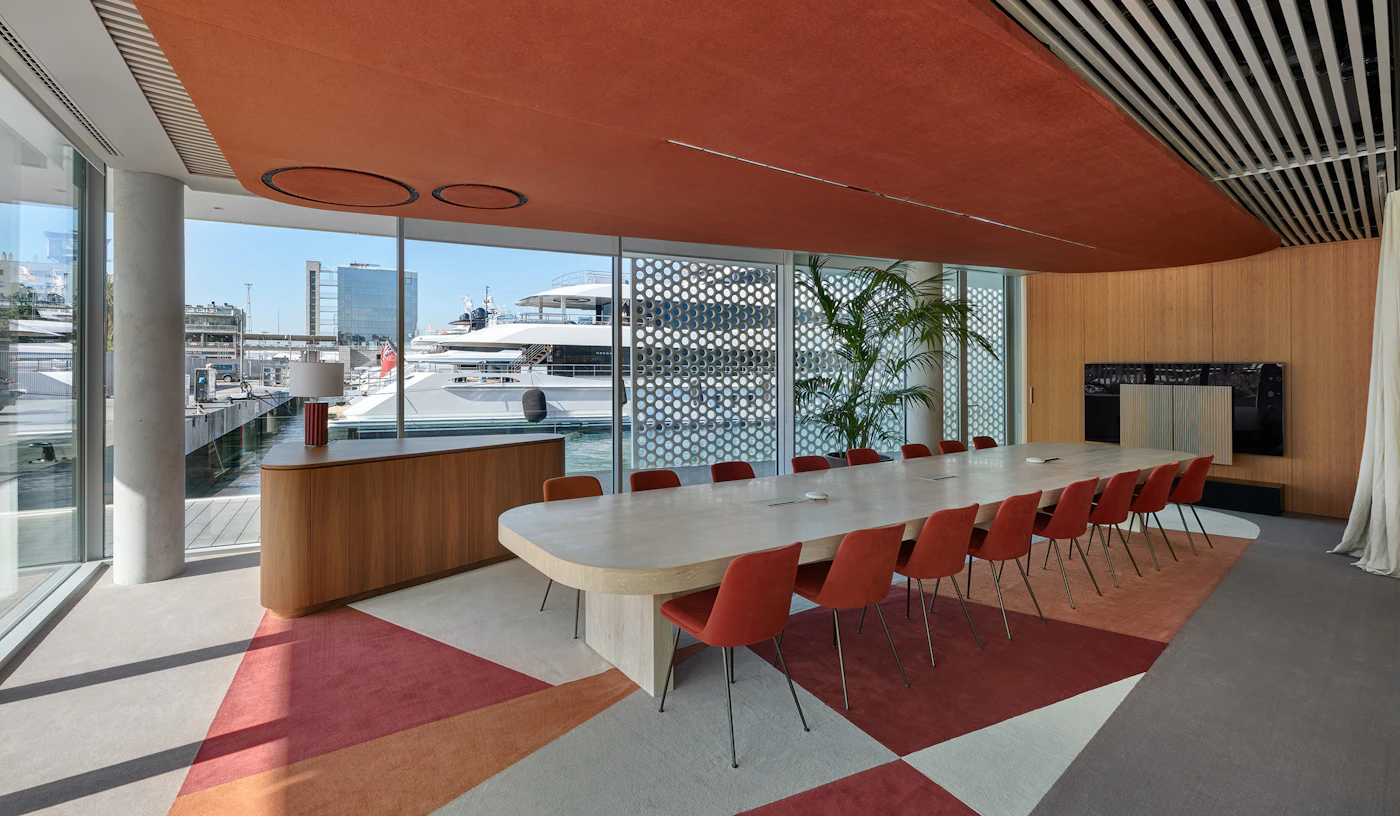 Meeting room with long table and orange chairs overlooking yachts in the marina.